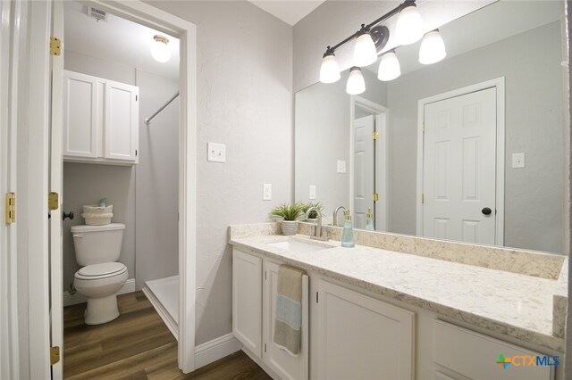 bathroom featuring a shower, vanity, hardwood / wood-style flooring, and toilet