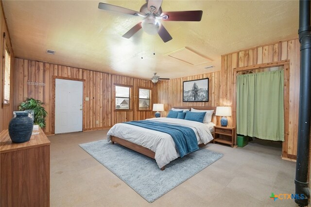 bedroom featuring ceiling fan, wood walls, and light colored carpet