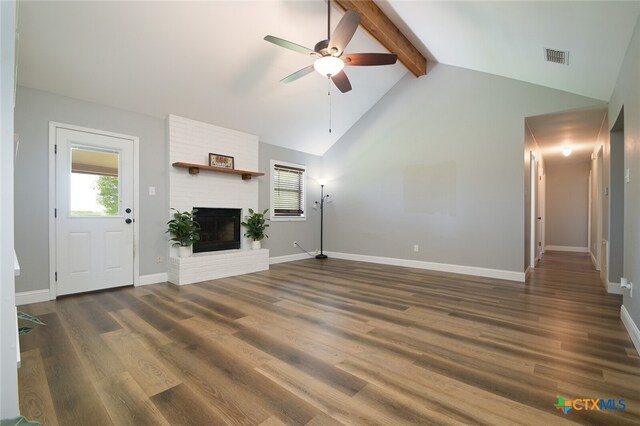 unfurnished living room with a fireplace, lofted ceiling with beams, ceiling fan, and dark wood-type flooring