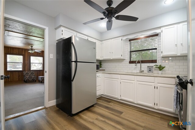 kitchen featuring backsplash, white cabinetry, stainless steel appliances, and wooden walls