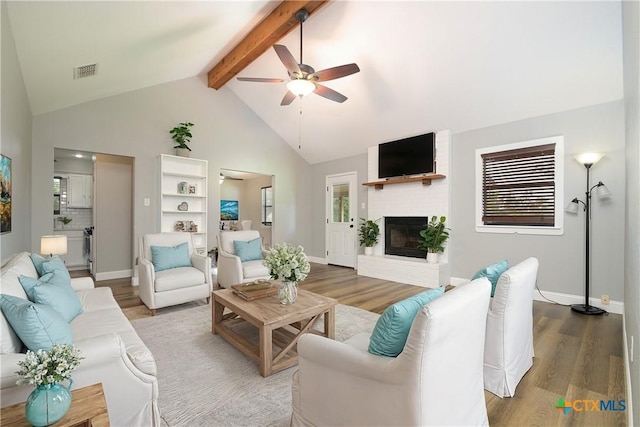 living room with beam ceiling, ceiling fan, high vaulted ceiling, hardwood / wood-style floors, and a fireplace