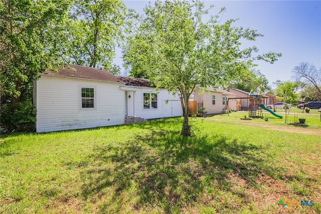 rear view of house with a lawn and a playground