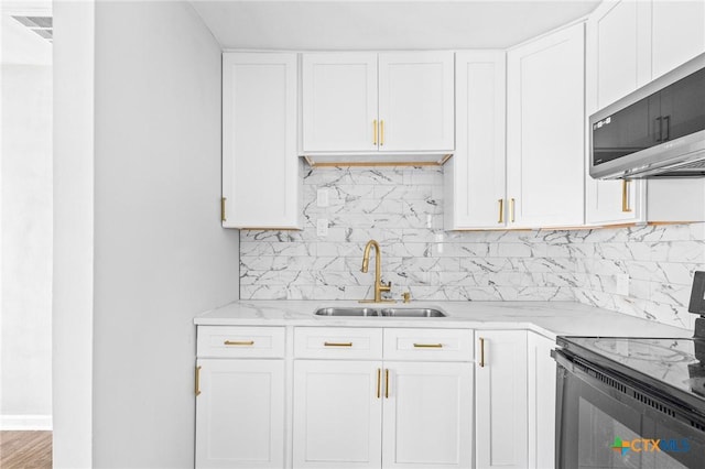 kitchen featuring stainless steel microwave, black / electric stove, white cabinetry, and a sink
