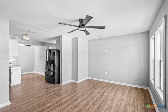 unfurnished living room with ceiling fan, baseboards, wood finished floors, and visible vents