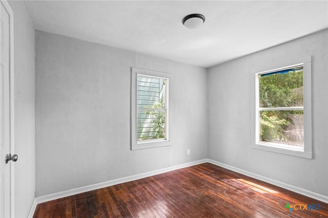 spare room with baseboards and dark wood-style flooring
