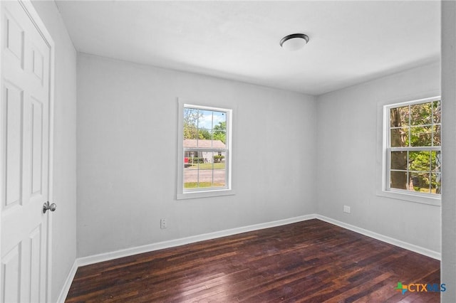 spare room featuring baseboards and dark wood-style flooring
