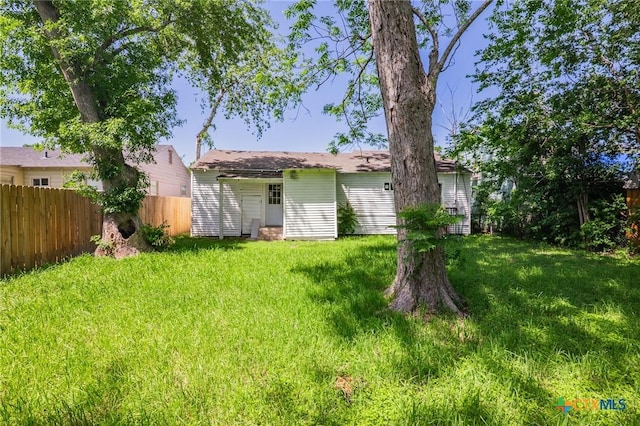 rear view of house featuring fence and a yard