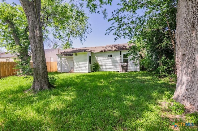 back of house featuring fence and a yard
