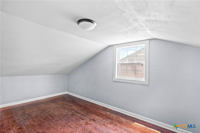 additional living space featuring vaulted ceiling, a textured ceiling, baseboards, and wood finished floors
