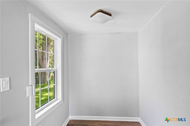 empty room featuring baseboards, wood finished floors, and a healthy amount of sunlight
