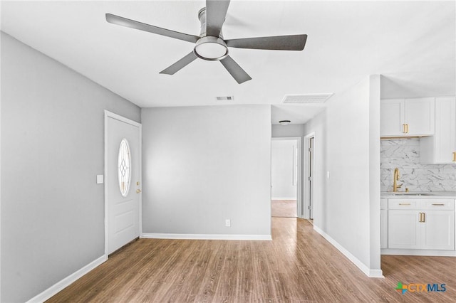 unfurnished living room featuring visible vents, light wood finished floors, baseboards, and ceiling fan
