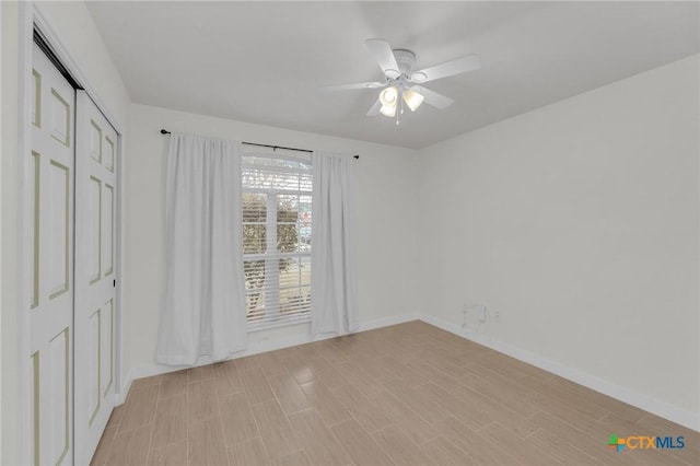 unfurnished bedroom with baseboards, a closet, light wood finished floors, and ceiling fan