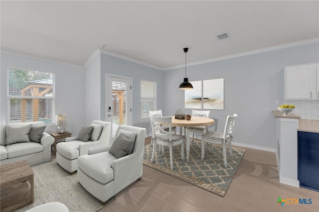 living area featuring crown molding, baseboards, visible vents, and light wood finished floors