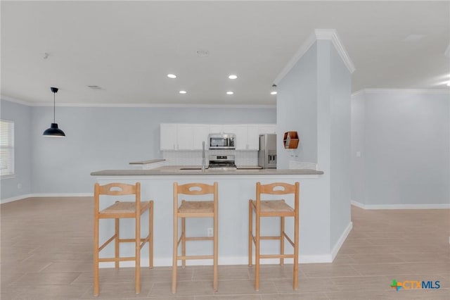 kitchen with a breakfast bar area, baseboards, stainless steel appliances, white cabinets, and backsplash