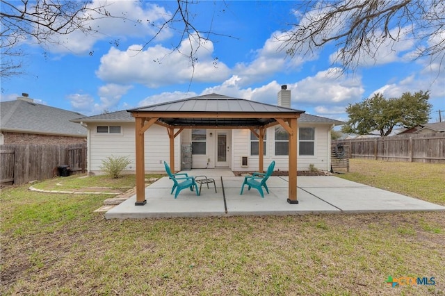 rear view of house featuring a patio, a yard, a fenced backyard, a chimney, and a gazebo