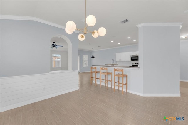 kitchen featuring visible vents, ceiling fan with notable chandelier, white cabinetry, appliances with stainless steel finishes, and a breakfast bar area