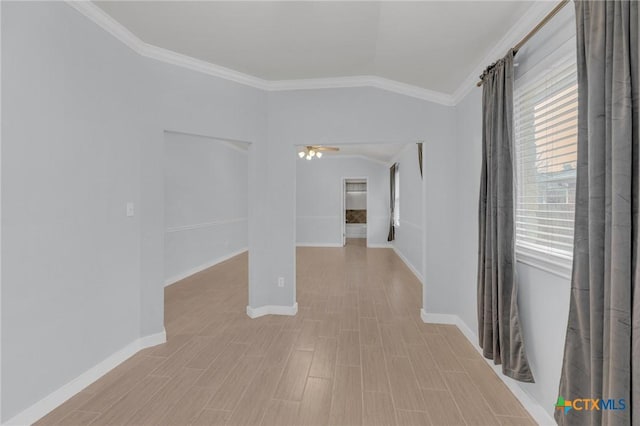 spare room with ornamental molding, baseboards, and vaulted ceiling