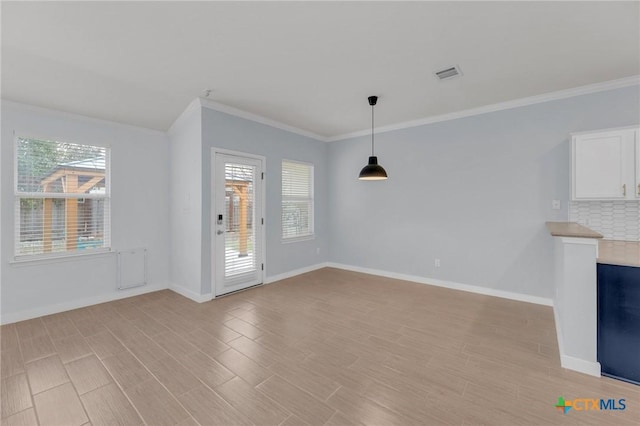 unfurnished living room featuring crown molding, light wood-style floors, visible vents, and baseboards