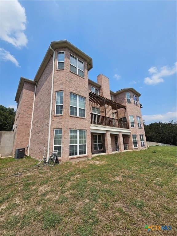 back of house featuring central AC unit and a yard