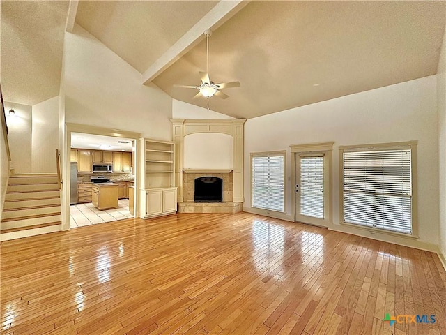 604 Dunbar Dr, Victoria, TX 77904 - unfurnished living room featuring ceiling fan, light wood-style flooring, high vaulted ceiling, stairs, and beamed ceiling