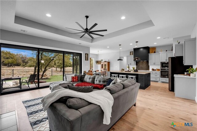 123 Wandering Oak Cir, Burnet, TX 78611 - living room featuring a tray ceiling, a ceiling fan, recessed lighting, and light wood finished floors