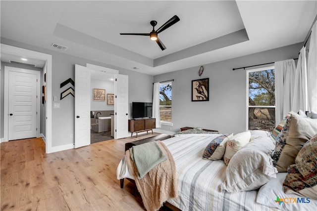 123 Wandering Oak Cir, Burnet, TX 78611 - bedroom with a tray ceiling, light wood-type flooring, baseboards, recessed lighting, and ensuite bath