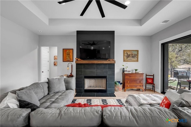 123 Wandering Oak Cir, Burnet, TX 78611 - living area with a ceiling fan, wood finished floors, a tray ceiling, and a tile fireplace