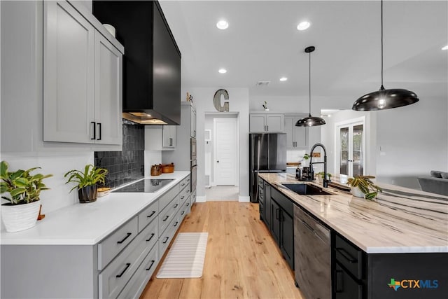 123 Wandering Oak Cir, Burnet, TX 78611 - kitchen featuring black appliances, a sink, tasteful backsplash, light wood-type flooring, and a spacious island