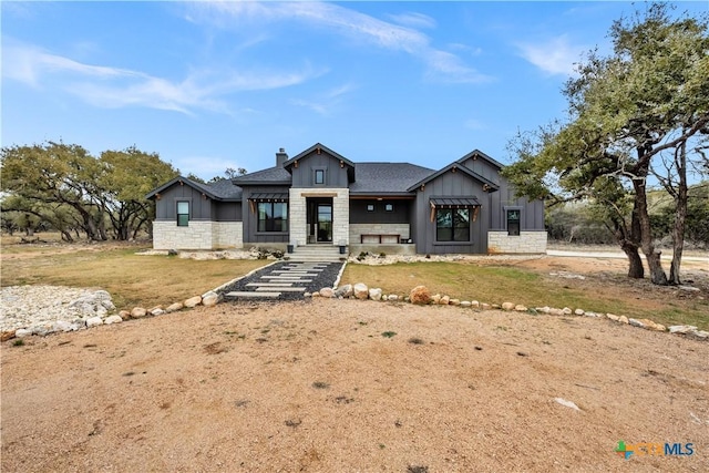 123 Wandering Oak Cir, Burnet, TX 78611 - view of front of house featuring board and batten siding, stone siding, a chimney, and a front yard