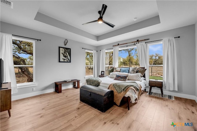 123 Wandering Oak Cir, Burnet, TX 78611 - bedroom with a tray ceiling, baseboards, light wood-type flooring, and access to outside