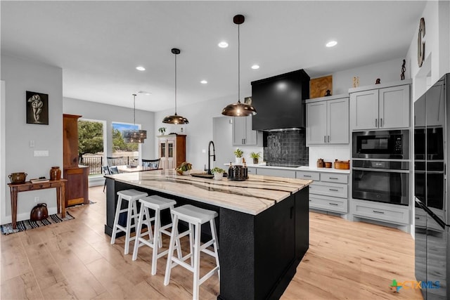 123 Wandering Oak Cir, Burnet, TX 78611 - kitchen featuring black appliances, custom exhaust hood, a spacious island, light wood-style floors, and recessed lighting