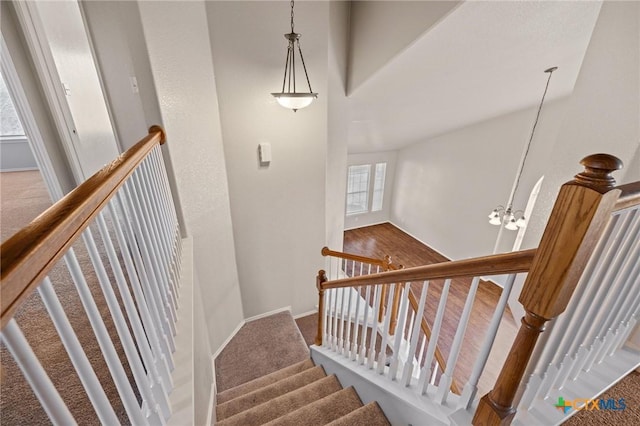 staircase featuring baseboards, carpet floors, and an inviting chandelier