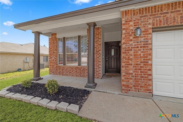 entrance to property with a porch, brick siding, a garage, and central air condition unit