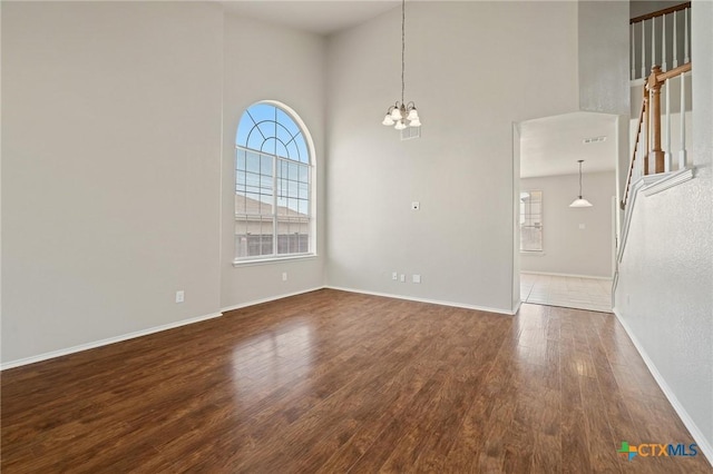 spare room featuring baseboards, visible vents, wood finished floors, stairs, and a notable chandelier