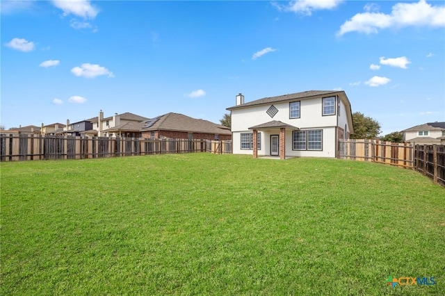 back of property with a fenced backyard and a lawn