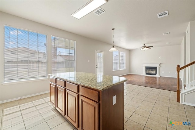 kitchen featuring a glass covered fireplace, visible vents, ceiling fan, and light tile patterned flooring