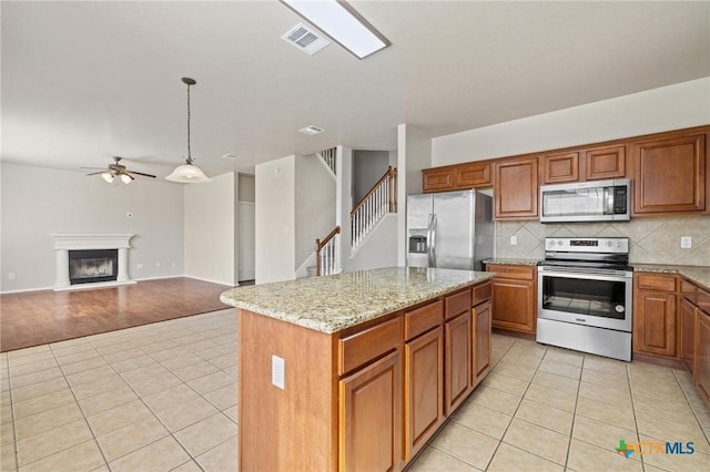 kitchen featuring appliances with stainless steel finishes, a glass covered fireplace, visible vents, and light tile patterned floors