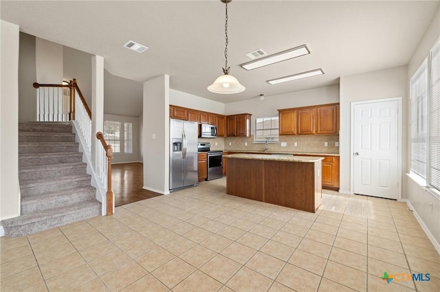 kitchen with light tile patterned floors, tasteful backsplash, visible vents, brown cabinetry, and stainless steel appliances