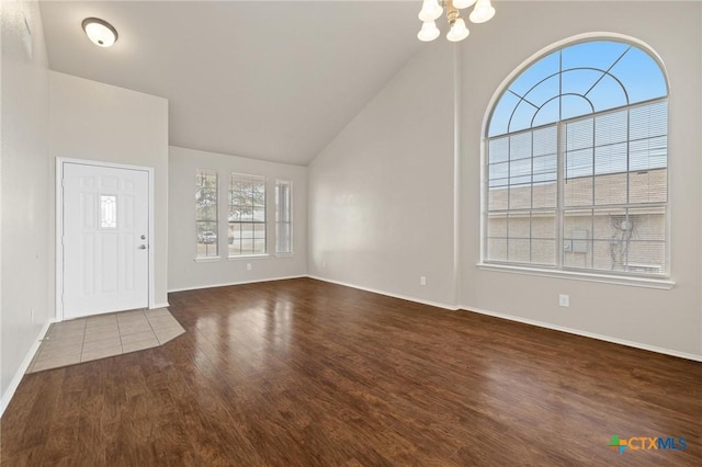 entryway featuring a chandelier, lofted ceiling, baseboards, and wood finished floors