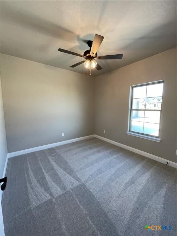 unfurnished room with dark carpet, a ceiling fan, and baseboards