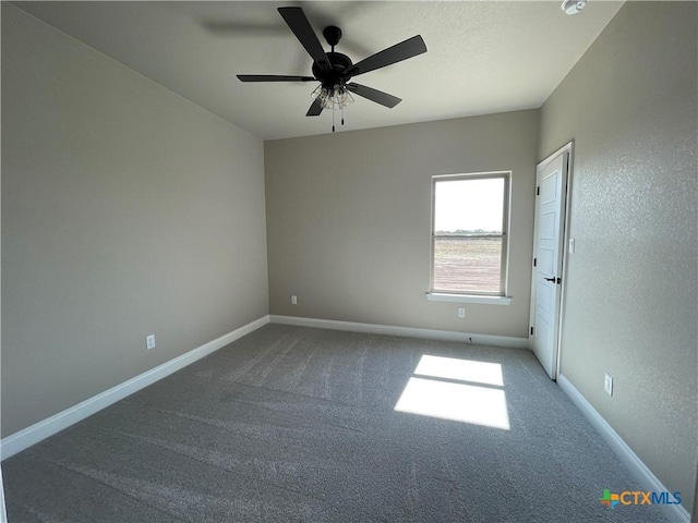 carpeted spare room featuring ceiling fan and baseboards