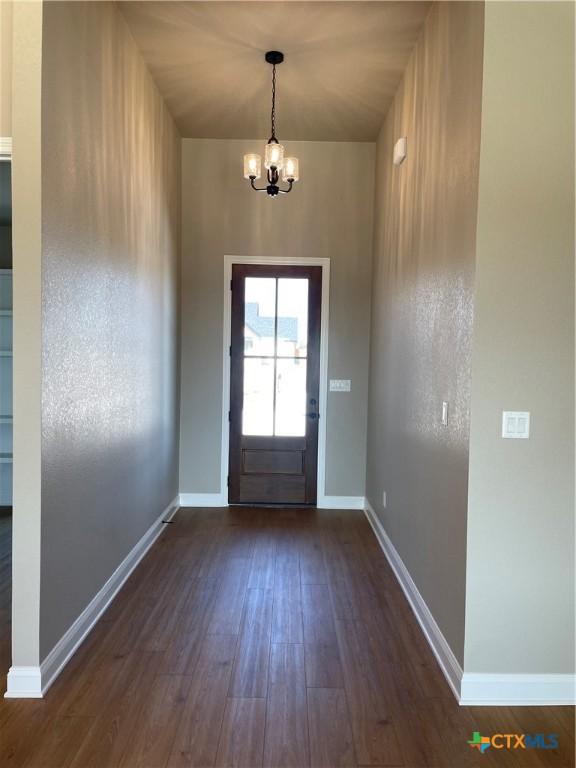 doorway featuring baseboards, dark wood finished floors, and a chandelier