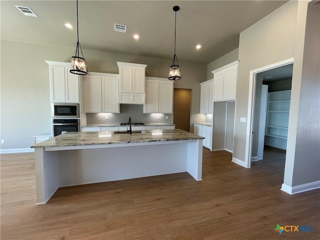 kitchen with visible vents, a center island with sink, appliances with stainless steel finishes, and wood finished floors