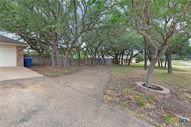 view of yard with driveway and fence