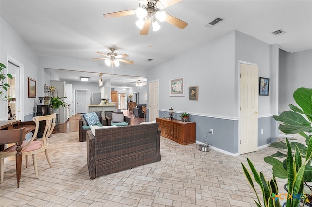 living room with baseboards, ceiling fan, brick floor, and visible vents