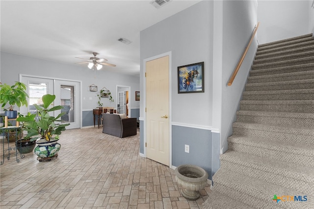 staircase with visible vents, a ceiling fan, brick floor, and baseboards
