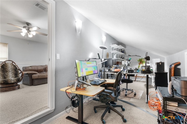 office area featuring carpet floors, vaulted ceiling, visible vents, a ceiling fan, and a textured ceiling