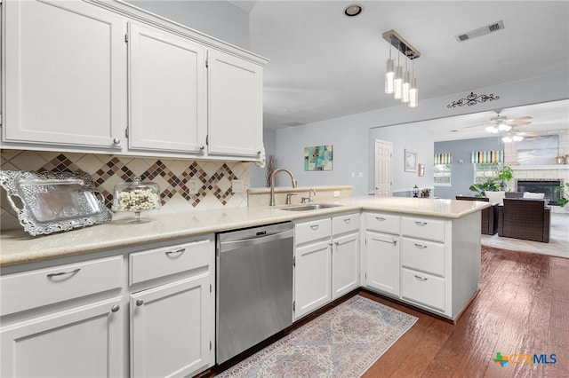 kitchen with light countertops, white cabinets, dishwasher, a sink, and a peninsula