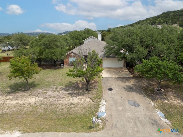 obstructed view of property featuring a chimney, a mountain view, driveway, brick siding, and an attached garage