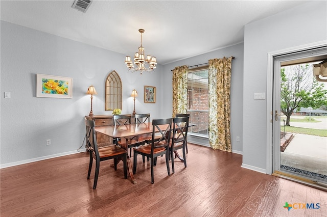 dining room with a notable chandelier, visible vents, wood finished floors, and baseboards